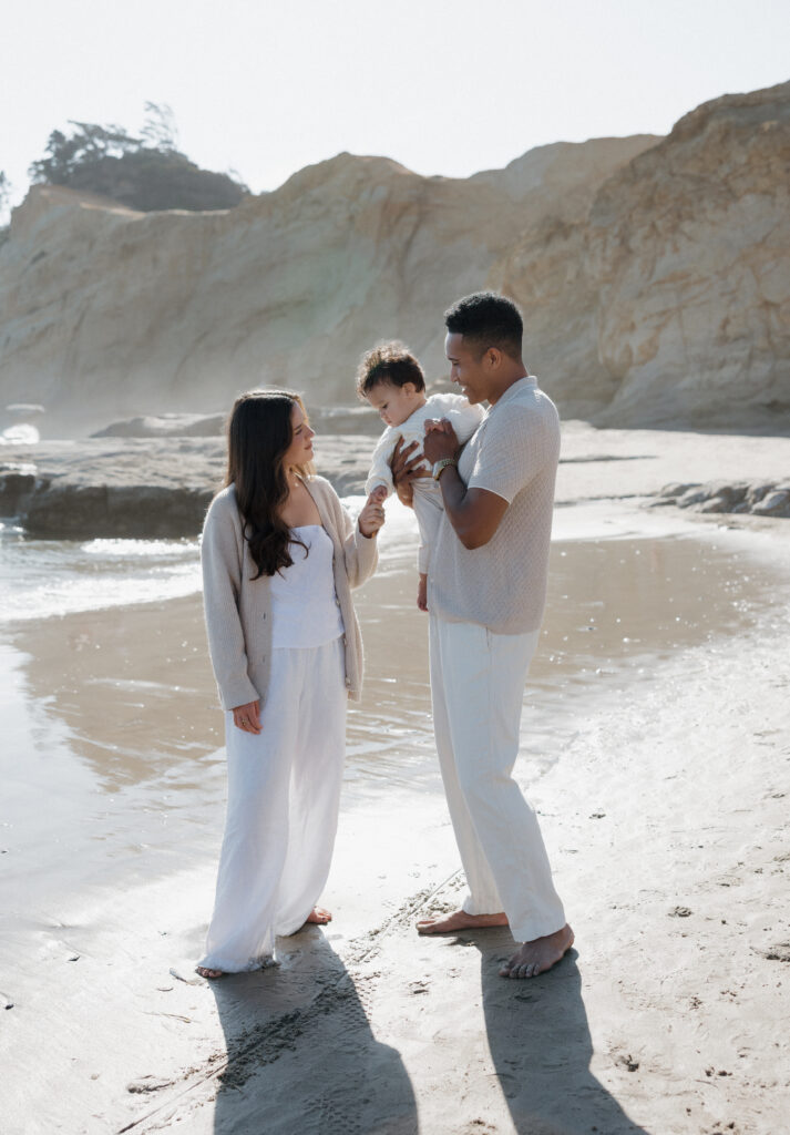 Loving couple embracing on Cape Kiwanda shoreline  
Joyful couple walking along the Cape Kiwanda beach  
Couple sharing a playful moment at sunset on Oregon Coast  
Intimate candid couple photography at Cape Kiwanda  
Parents holding their baby close by the ocean  
Family enjoying tender moments on Cape Kiwanda sand  
Sunset family portraits on Oregon Coast  
Baby boy snuggled with parents on Cape Kiwanda beach  
Majestic cliffs along Cape Kiwanda coastline  
Rocky sandstone formations at Oregon Coast  
Golden sunset light over Cape Kiwanda shore  
Parents laughing with baby on Oregon Coast  
Playful family interactions on Cape Kiwanda beach  
Warm evening glow along Oregon Coast coastline  
Ocean sunset behind couple at Cape Kiwanda